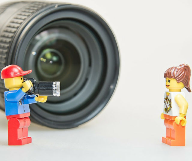 Lego people taking a photo with camera lens in background