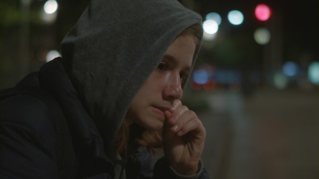 young girl with hood up crying