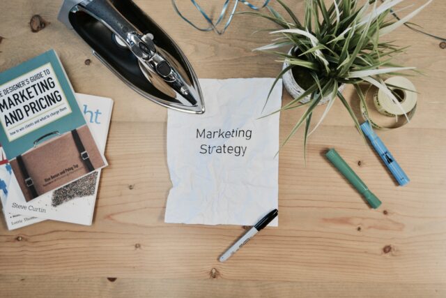 marketing strategy written on creased sheet of paper with pens and books around it