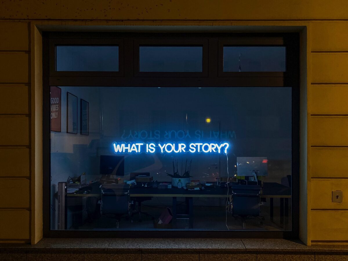 'What is your story' written on window in neon lights