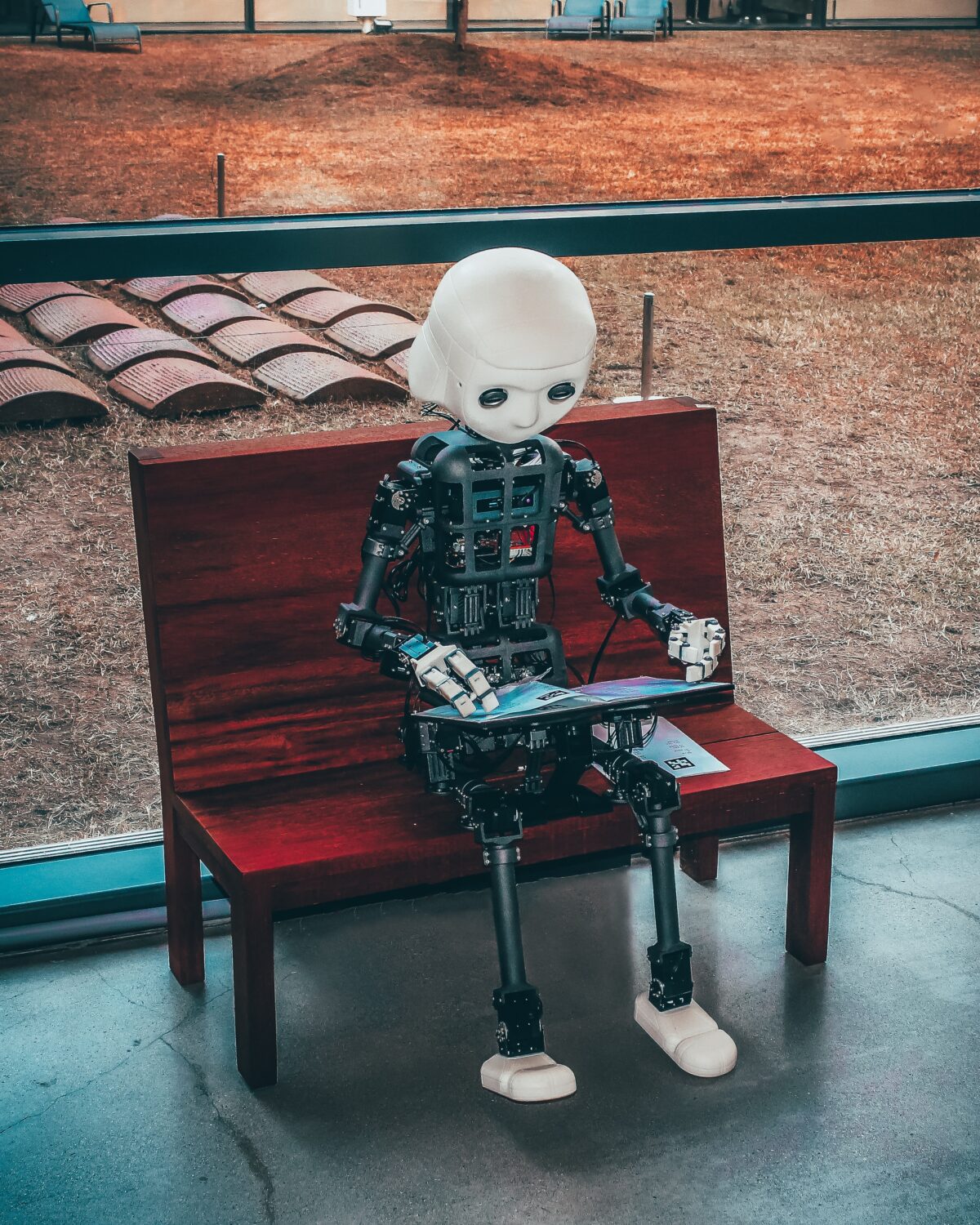 Robot sitting on a bench typing on an iPad