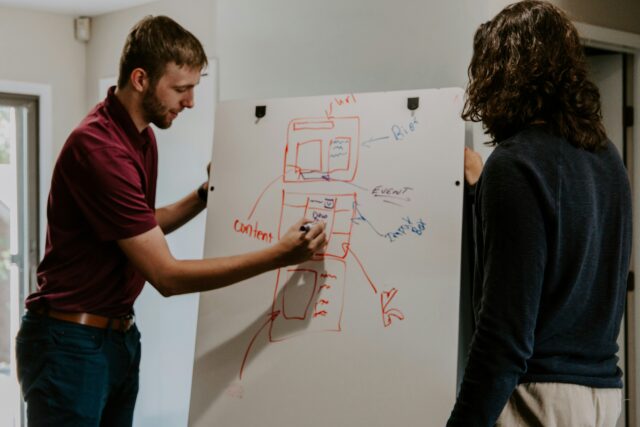 two people in front of a whiteboard learning/planning a marketing strategy involving organic activity that all ties into SEO